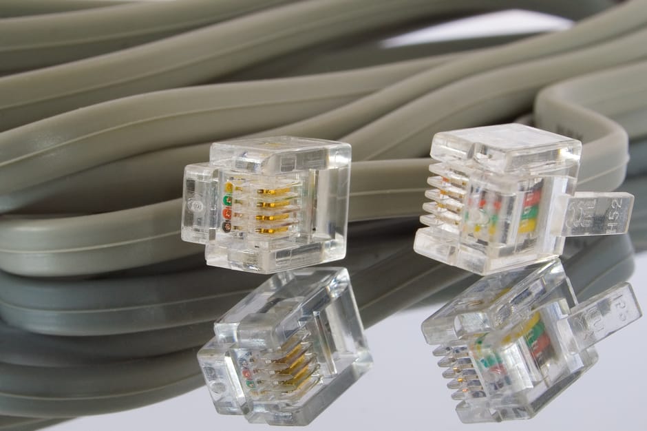 The image displays a neatly coiled bundle of light grey plastic Ethernet cables, with four transparent RJ45 connectors placed on top of the cables in a scattered arrangement. The connectors reveal int